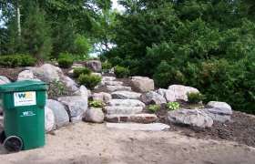 Boulder landscape and retaining wall with cut boulder steps
