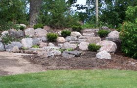 Side view of a boulder landscape and retaining wall with cut boulder steps