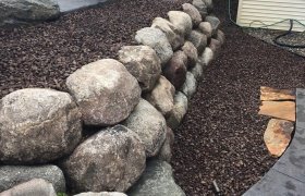Three stacked rows of boulders installed as a retaining wall