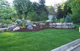 Front yard flower planter complete with boulder accents and shrubs