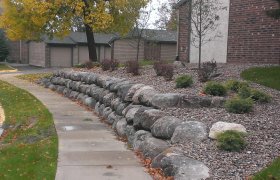 Boulder retaining wall and rock landscape along a sidewalk