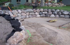 Paver patio with boulder retaining wall in the process of being installed
