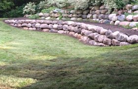 Multi-tiered retaining wall made from fieldstone boulders