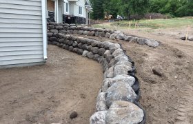 Newly finished boulder retaining wall with fresh backfilled aggregate