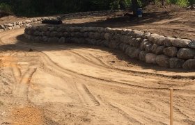 Curved boulder retaining wall running along each side of a driveway