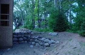 Small boulder retaining wall along the side of a house