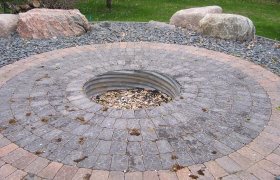 Circular paver patio around a sunken firt pit with fieldstone boulders as seating areas