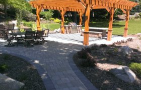 Large backyard paver patio with a wood pergola sitting area