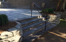 Raised paver patio with paver steps and wrough iron handrail