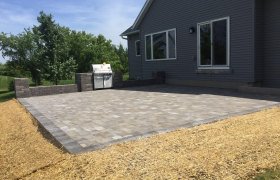 Newly finished backyard paver patio in a square shape