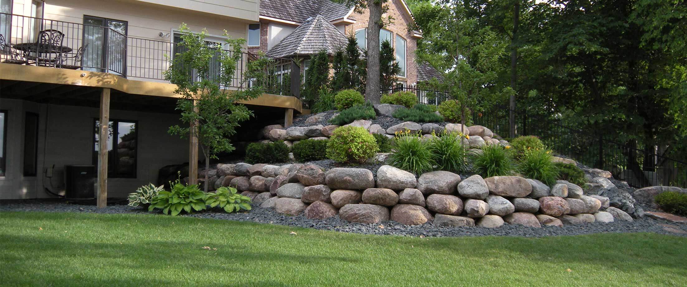Fieldstone Boulder retaining wall and plant garden in the backyard of a residential home